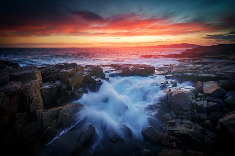 Rick Berk Notecard Set photo: the October sky over Schoodic Point glows red as the sun sets behind Cadillac Mountain in Acadia National Park, Maine
