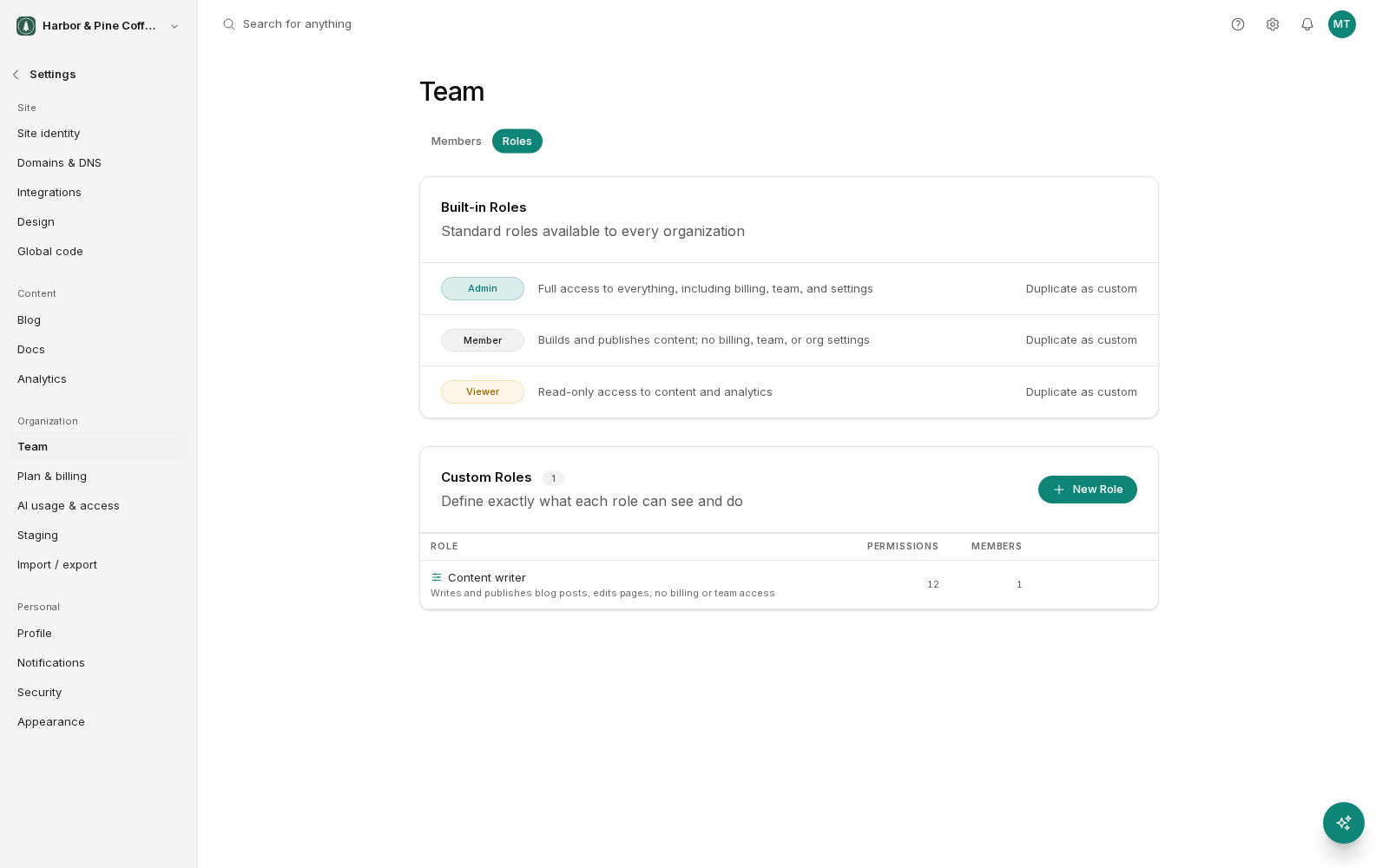 The Roles tab of the Team settings screen. A Built-in Roles card describes Admin, Member and Viewer, each with a Duplicate as custom link. A Custom Roles card below has a New Role button and lists one role, Content writer, with its description, 12 permissions and 1 member.