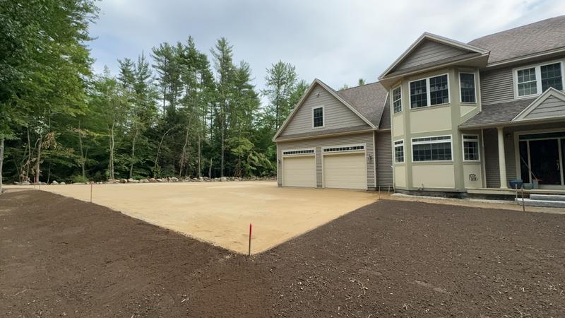 Excavator shaping a residential driveway
